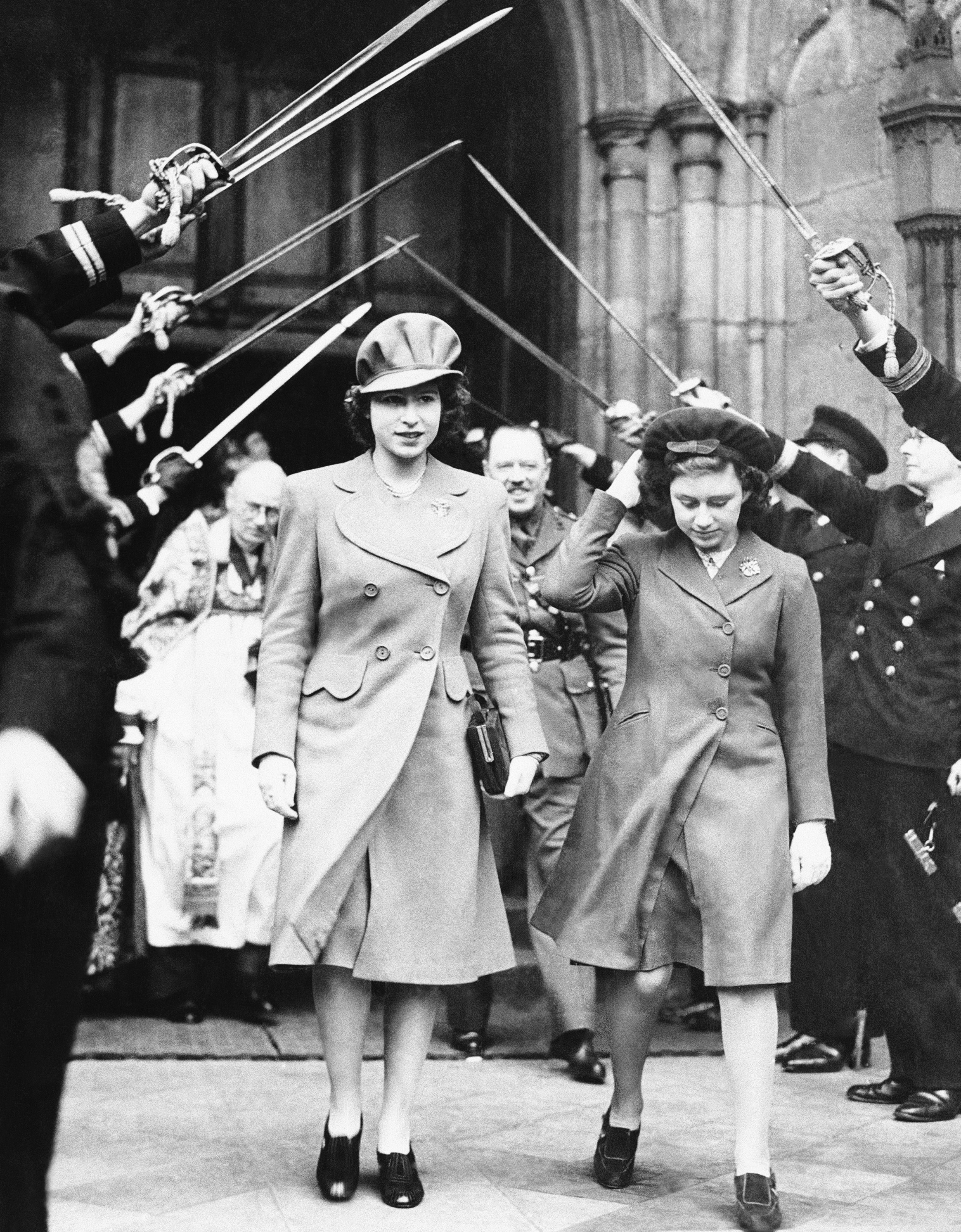 Princess Elizabeth, left, and Princess Margaret Rose of England leave Westminster Abbey through an arch of crossed swords after attending the wedding of Lady Anne Spencer, a distant cousin of Prime Minister Winston Churchill and aunt of the future Diana, Princess of Wales, to Lt. C. Wake-Walker, son of the Third Lord of the Admiralty, Feb. 20, 1944, London, England.